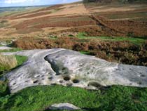 Channel rock showing cup marks and view across valley